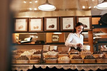 Confectionery. Woman Selling Chocolate Candies In Store