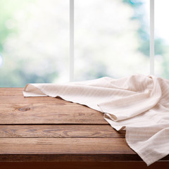 Empty wooden table with tablecloth near the window in kitchen. Napkin close up top view mock up. Kitchen rustic background with window.