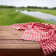 Red checkered tablecloth on wooden table. Napkin close up top view mock up. Summer rustic background.