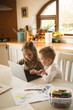 © Wavebreak Media - Children using laptop together in kitchen