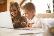 © Wavebreak Media - Children using laptop together in kitchen