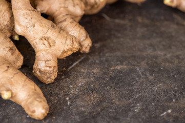 Whole ginger roots on dark old stone background table top view space for text.