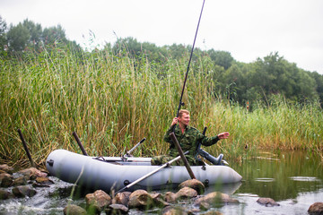 Wall Mural - Fisherman catching fish on the river from rubber boat.