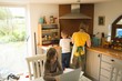 © Wavebreak Media - Mother and son preparing food while daughter using laptop in