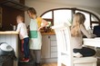 © Wavebreak Media - Mother and son preparing food while daughter using laptop in