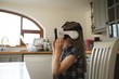 © Wavebreak Media - Side view of girl using virtual reality headset while sitting in kitchen