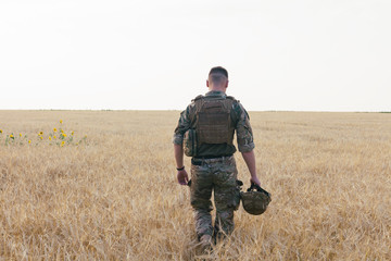 Wall Mural - Soldier man standing against a field. Portrait of happy military soldier in boot camp. US Army soldier in the Mission. war and emotional concept.