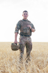 Wall Mural - Soldier man standing against a field. Portrait of happy military soldier in boot camp. US Army soldier in the Mission. war and emotional concept.
