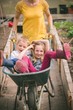 © Wavebreak Media - Mother having fun with kids in wheelbarrow