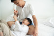 © ic36006 - Happy family. Dad and son playing and laughing in bed room.