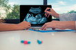 © steph photographies - Doctor showing a scan of fetus on a laptop to a woman patient. Healthcare about baby during pregnancy concept. Pills or drugs on the desk