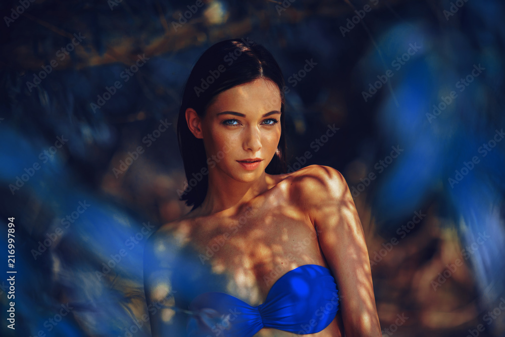 Beautiful young woman in a bikini in the shade under the tree - obrazy, fototapety, plakaty 