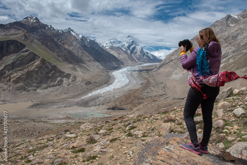 Traveller woman with DSLR camera standing to take a beautiful landscpe image of D rang-Drung Glacier, Mountain glacier on zanskar road at Himalaya Range, Zanskar Range, Pensi La, Jammu and Kashmir Canvas Print