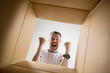 © master1305 - The surprised man unpacking, opening carton box and looking inside. The package, delivery, surprise, gift lifestyle concept. Human emotions and facial expressions concepts