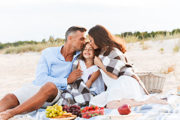 Wall Mural - Parents hugging outdoors at the beach with their daughter.