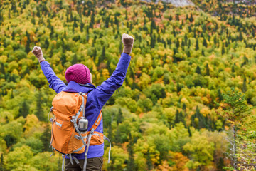 happy autumn hiking success winner woman with win arms up hiker cheering in fall nature background.