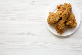 Fototapeta Góry - Fried chicken legs on a white round plate with copy space, overhead view. From above, top view, flat lay.