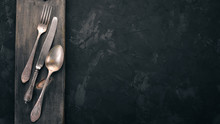 Old Cutlery. On A Black Stone Background. Top View. Free Space For Text.