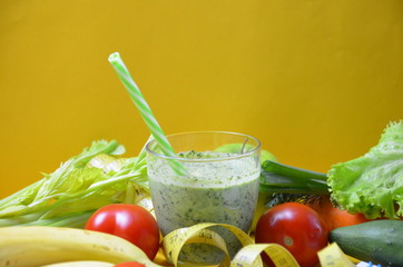 Green healthy juice with fruits and vegetables different colors on yellow background close up, copy space. diet vegitarians healthy low-calorie food