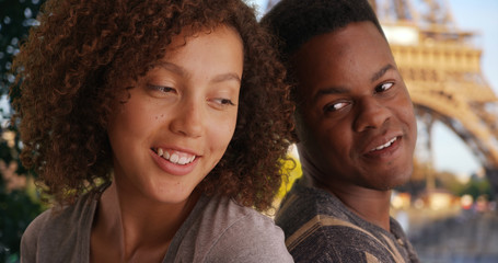 Wall Mural - Cute African American couple sit back to back near Eiffel Tower smiling