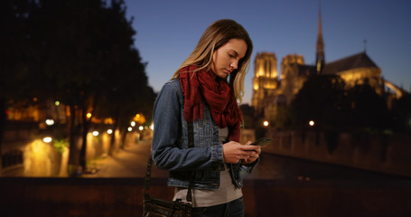 Wall Mural - Stylish girl in Paris messaging on smartphone at night
