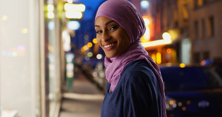 Wall Mural - Beautiful young Muslim woman in urban setting smiling at camera