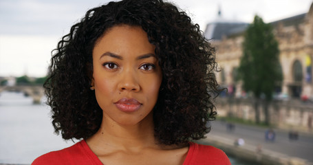 Poster - African-American woman with serious look on face standing outside by Seine River