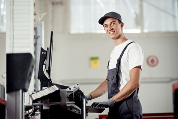 Wall Mural - An attractive mechanic is smiling while conducting the diagnosis of a car