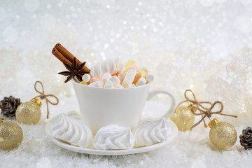 Wall Mural - Cup of hot beverage with marshmallow and spices on snow background.