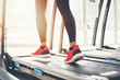 © tuiphotoengineer - Blurry of  running sport shoes at the gym while a young caucasian woman is having jogging on the treadmill