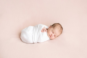 newborn girl in white wrap on a pink background. photoshoot for the newborn. 7 days from birth. a po