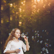 © ulkas - curly girl blowing soap bubbles.