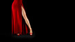 © Stavros - unrecognizable sexy female legs in a red dress and high heeled shoes on a black background.