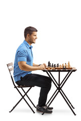 Wall Mural - Young guy seated at a table playing chess