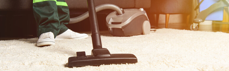 Cropped shot of professional worker using vacuum cleaner and cleaning white carpet