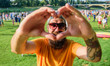 © be free - Man bearded hipster in front of crowd people show heart gesture riverside background. Hipster happy celebrate event picnic fest or festival. Urban event celebration. Cheerful fan love summer fest