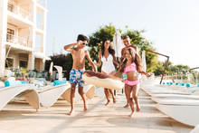 Image Of Happy Caucasian Family With Children Resting Near Luxury Swimming Pool, With White Fashion Deckchairs And Umbrellas Outside Hotel