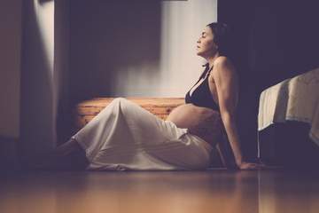 pregnant beautiful caucasian woman sitting on the floor and breathe to relax. new life concept at home