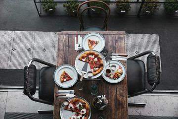 Wall Mural - top view of delicious pizza and curd pancakes on wooden table at restaurant