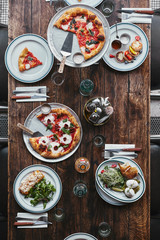 Wall Mural - top view of various tasty italian dishes and drinks on wooden rustic table at restaurant