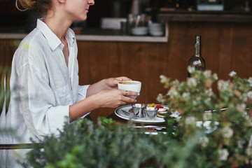 Wall Mural - cropped shot of young woman holding cup of coffee at restaurant