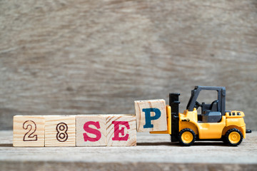 Wall Mural - Toy forklift hold block P to complete word 28 sep on wood background (Concept for calendar date in month September)