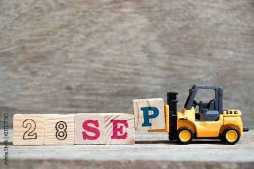 Fotografia Toy forklift hold block P to complete word 28 sep on wood background (Concept fo
