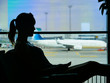 SILHOUETTE: Passenger holding her phone while looking through the airport window