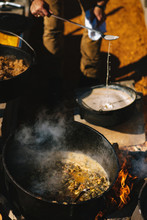 An Outdoor Cook Works With Gravy Over An Open Fire