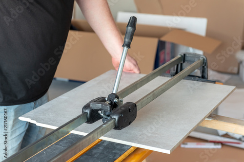 Fotografie, Obraz The man is cutting the floor tiles using a tile cutter machine.