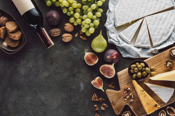 Wall Mural - top view of assorted cheese, bottle of wine and fruits on dark tabletop