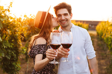 Poster - Cute happy loving couple outdoors drinking wine looking camera.