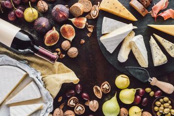 Wall Mural - food composition with cheese, bottle of wine and fruits on dark tabletop