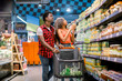 © sofiko14 - African young Couple with shopping trolley shopping in supermarket grocery aisle